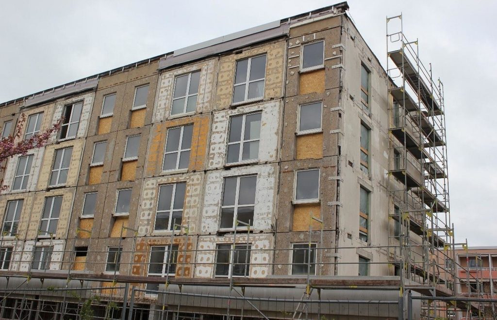 Die alte Fassade wurde entfernt, sodass nur noch der nackte Beton zu sehen ist. An der Stirnseite wurden bereits die Fenster entfernt.